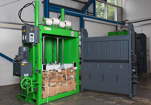 large green phs wastekit baler with compressed cardboard inside