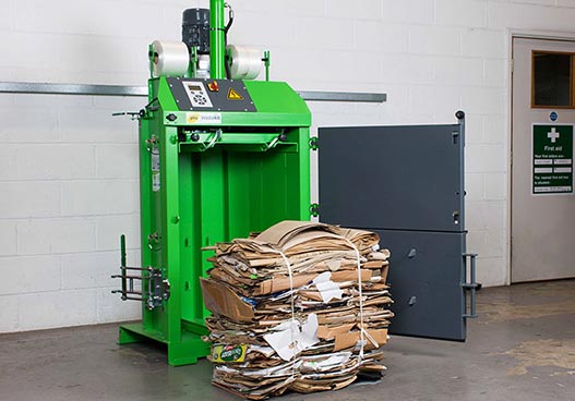 phs wastkite green baler with a cardboard bale sat in front of the baler