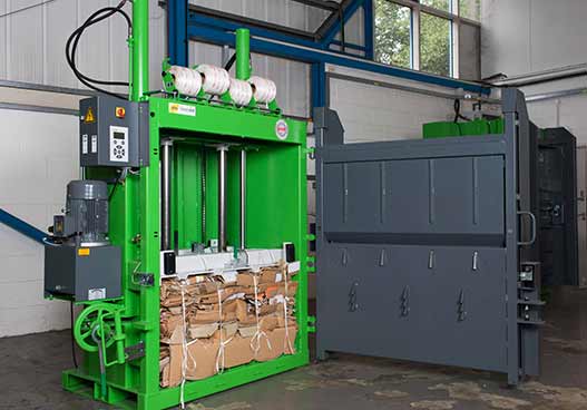 large green baler filled with compressed cardboard phs waste kit