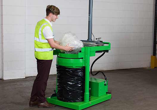 phs waste kit employee placing waste plastic inside a green bag compactor